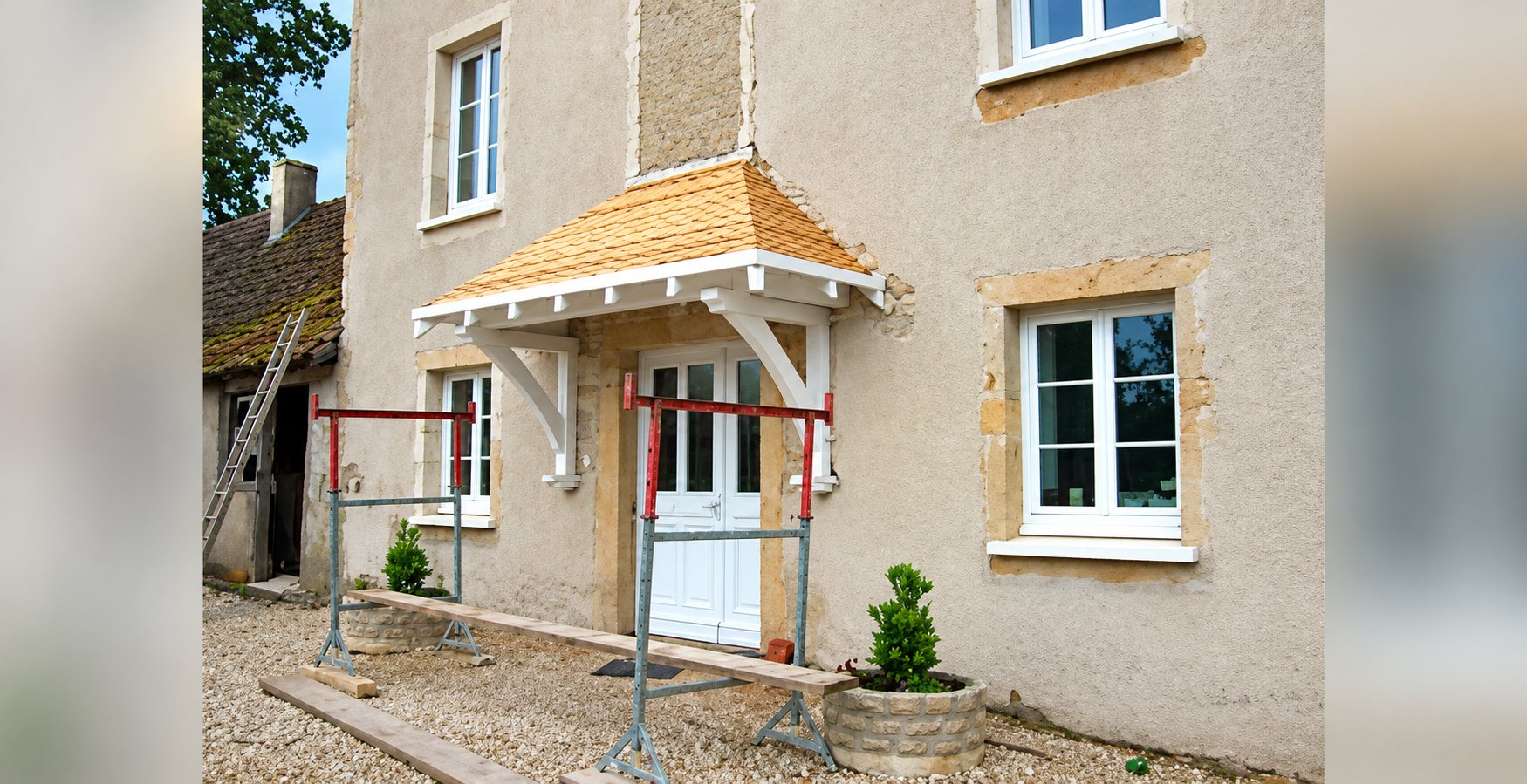 Façade de maison rénovée avec auvent en bois au-dessus de la porte
